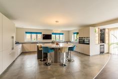 a large kitchen with an island table surrounded by blue chairs