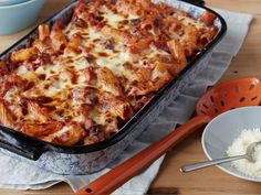 a casserole dish with meat and cheese in it on a table next to two bowls