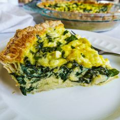 a slice of quiche with spinach and cheese on it sitting on a plate