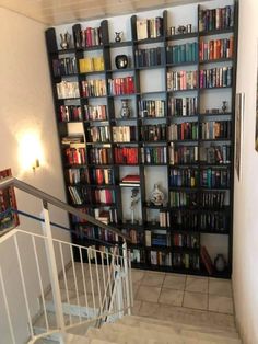 there is a book shelf with many books on it and stairs leading up to the second floor