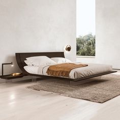 a modern bedroom with white walls and wood flooring, along with a large window