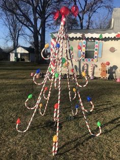 a christmas tree made out of candy canes in front of a mobile home on the lawn