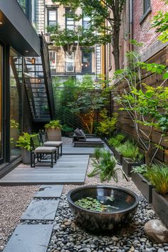 an outdoor garden with rocks, plants and water features in front of the stairs leading up to the second floor