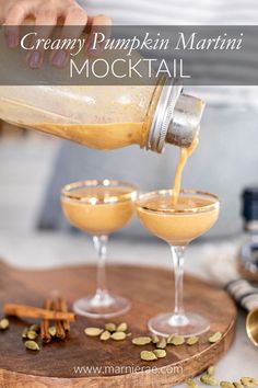 a person pouring pumpkin martini into glasses on a cutting board with spices and cinnamons