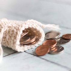 a small crochet bag filled with coins on top of a tile floor next to a pile of pennets