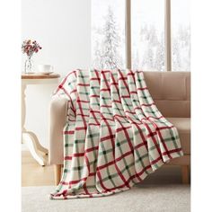 a living room with a couch and window covered in a red and green plaid blanket