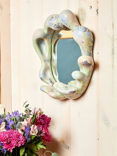 a vase with flowers sitting next to a mirror on a wall near a planter