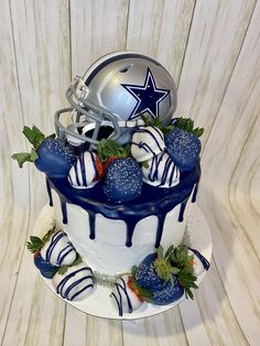 a football themed cake with strawberries on top and a helmet on the top tier