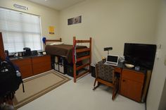 a dorm room with bunk beds and desks