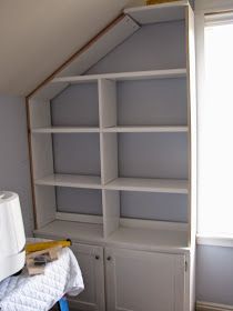 a white bookcase in the corner of a room next to a lamp and window