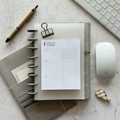 a notepad, keyboard and mouse on top of a desk