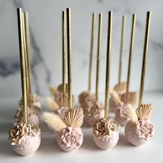 there are some pink and gold cake pops with flowers on them next to each other