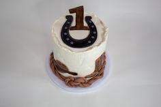 a birthday cake decorated with a horseshoe and rope on a white tablecloth covered plate