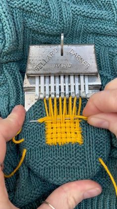 someone is using a small comb to sew on some knitting material that has been stitched together