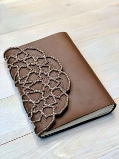 a brown leather journal sitting on top of a wooden table