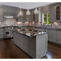 a large kitchen with an island in the middle of it and several lights hanging from the ceiling