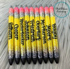 six yellow and pink glittered crayons are lined up on a furry surface