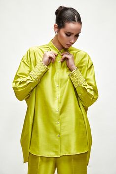 Lime green button down asymmetric shirt with detailed broad pearl embroidered cuffs and pleated detailing at back. Paired with pant.
Components: 2
Pattern: Embroidered
Type Of Work: Pearl
Neckline: Shirt collar
Sleeve Type: Bishop
Fabric: Silk blend
Color: Green
Other Details: 
Button placket
Embroidered cuffs
Asymmetric detailing
Occasion: Party - Aza Fashions Elegant Tops With Embroidered Cuffs, Green Blouse With Button Cuffs For Daywear, Elegant Green Tops With Button Cuffs, Elegant Green Blouse With Button Cuffs, Elegant Summer Blouse With Embroidered Cuffs, Asymmetric Shirt, Embroidered Cuffs, Pant Sets, Green Button