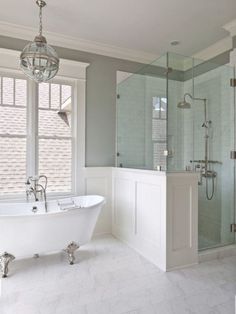 a white bath tub sitting in a bathroom next to a window with two chandeliers