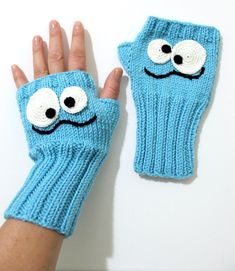 a person wearing blue knitted mitts with googly eyes on their fingertipss