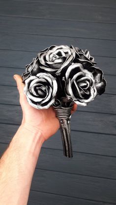 a hand holding a bouquet of black and white roses