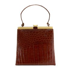 This luxurious cognac shiny alligator bag is beautifully made and features gold-color hardware & closure, and a roomy lined interior designed to carry your daily essentials. Detailed Features 10.5 x 10 x 9.75 inches (Length x Width x Depth) Can be carried by hand Gold-finish hardware Interior zip pocket Interior slip pocket Leather lining Handle: Single Strap: 7 inches Alligator cannot be sold or shipped to California. Cognac Bag, Beautifully Made, Daily Essentials, Office Wear, Fashion Handbags, Gold Finish, Alligator, Cognac, Zip Pockets