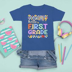 a t - shirt that says hello first grade next to some school supplies