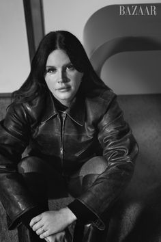 a woman sitting on top of a couch wearing a leather jacket