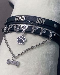 two bracelets with dog paw, heart and bone charms on black leather cord that says good boy puppy