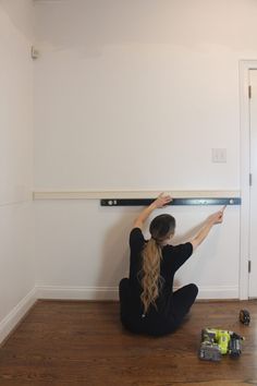 a woman is sitting on the floor working on a wall