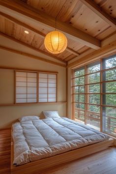 a bed sitting in the middle of a bedroom next to a window with lots of windows