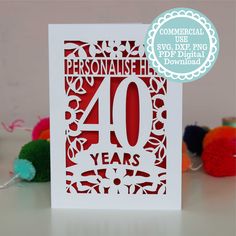 a red and white card with the number forty years printed on it, surrounded by pom poms