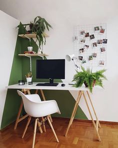 a desk with two chairs and a computer on top of it in front of a green wall