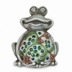 a frog figurine sitting on top of a white surface with green and blue accents