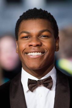 a close up of a person wearing a suit and bow tie smiling at the camera