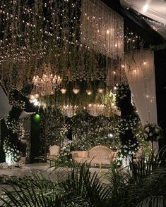 a room filled with lots of white flowers and greenery hanging from it's ceiling