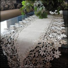 a white table cloth with flowers and leaves on the top, sitting on a couch