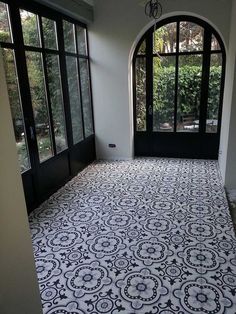 an empty room with black and white flooring in front of two large arched windows