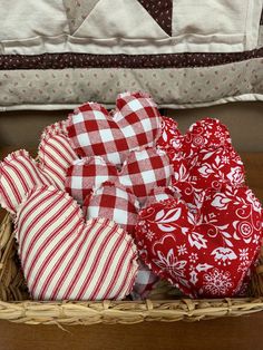 a basket filled with red and white hearts on top of a wooden table next to a pillow