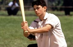 a young man holding a baseball bat on top of a field