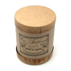 a white sage candle in a round wooden box on a white background with an old fashioned label