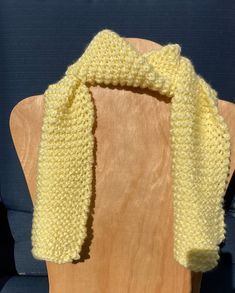 a yellow knitted scarf sitting on top of a wooden chair