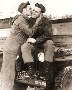 an old photo of two men kissing on the back of a truck