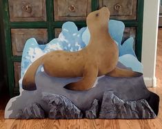 a statue of a sea lion sitting on top of a rock in front of some drawers