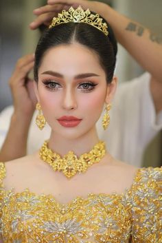 a woman wearing a gold tiara and matching jewelry with her hair in a bun