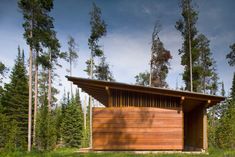 a wooden structure in the middle of a forest with lots of tall trees around it