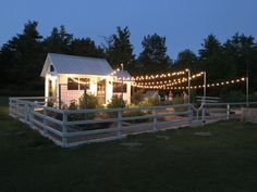 a small white building with lights on it's roof and some trees in the background