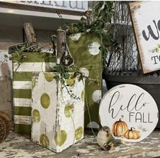 three small boxes with pumpkins on them are sitting on a shelf in front of a sign that says hello fall