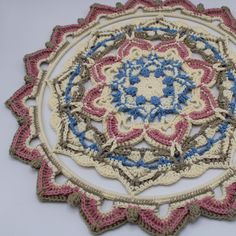 a crocheted doily with blue, pink and white flowers on it's center