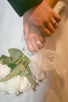 the bride and groom are holding hands with their wedding rings on top of each other